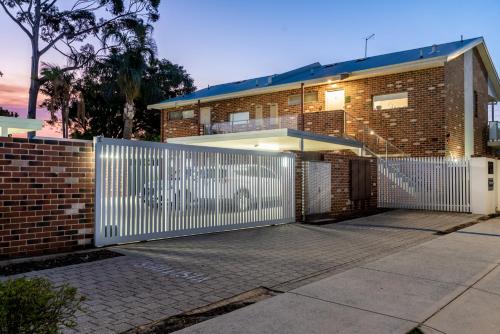 a brick house with a white fence in front of it at Happy Stays Classic Mid-Century Modern Escape in Perth