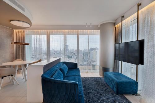 a living room with a blue couch and a tv at Port Tower by Isrotel Design in Tel Aviv