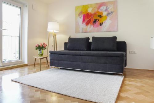 a blue couch in a living room with a rug at Bright Apartment in Ljubljana