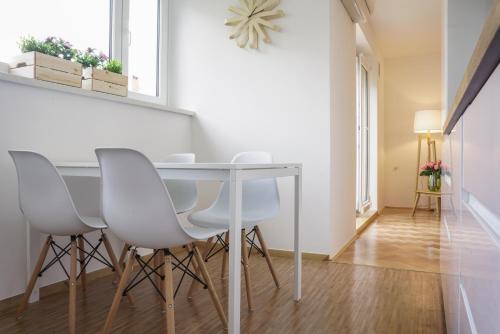 a dining room with a table and white chairs at Bright Apartment in Ljubljana