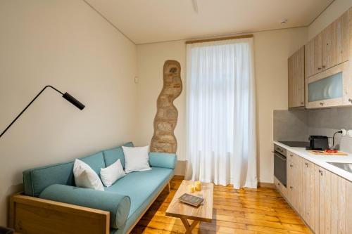 a living room with a blue couch and a kitchen at Eramai in Patra
