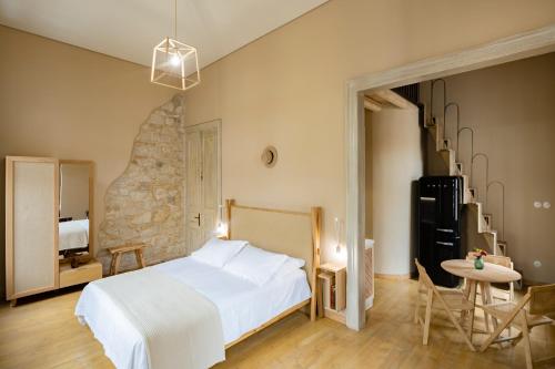 1 dormitorio con 1 cama blanca, mesa y sillas en Eramai en Patras