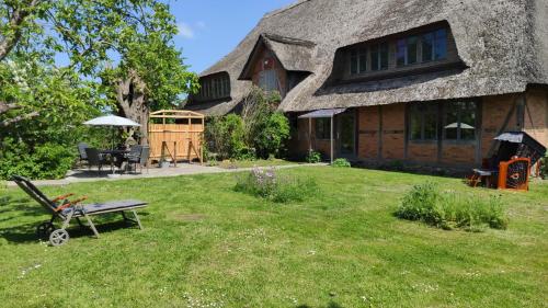 a house with a grass yard with a bench in front of it at FeWo Strohbrück in Quarnbek