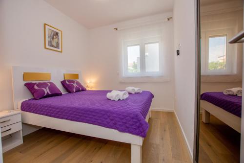 sypialnia z 2 łóżkami z fioletowymi prześcieradłami i lustrami w obiekcie Apartman Goldy w mieście Zadar