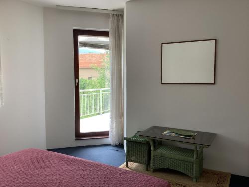 um quarto com uma cama, uma mesa e uma janela em Villa Nora Garden em Saraievo