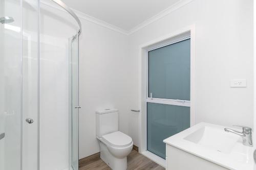 uma casa de banho branca com um WC e uma cabina de duche em vidro. em Comfy Stay Close to City Center em Hamilton