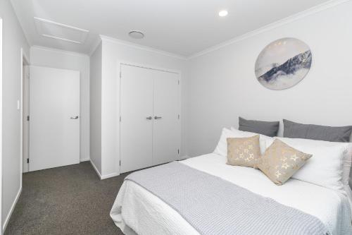 a white bedroom with a large white bed with pillows at Comfy Stay Close to City Center in Hamilton