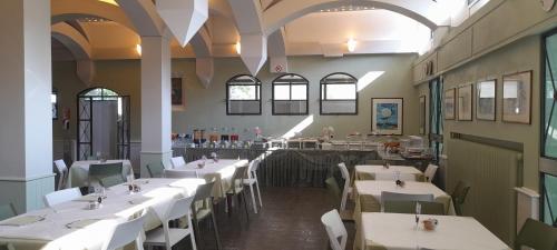 a restaurant with white tables and chairs and a bar at Hotel Maddalena in Marina di Ravenna