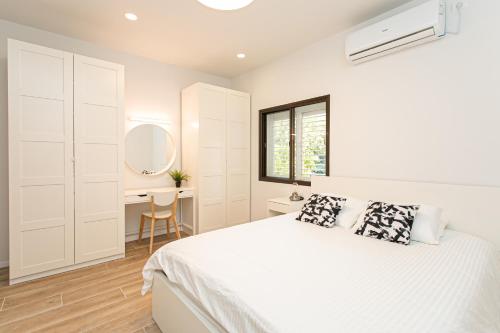a white bedroom with a bed and a desk at Carmel Boutique Apartments in Haifa