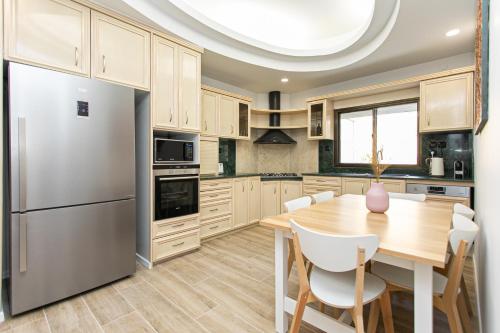 a kitchen with a wooden table and a stainless steel refrigerator at Carmel Boutique Apartments in Haifa