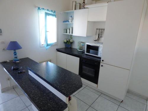 una cucina con armadi bianchi e piano di lavoro nero di Appartement T3 climatisé avec vue sur mer a Fleury