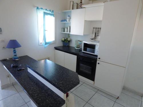 弗勒里Appartement T3 climatisé avec vue sur mer的厨房配有白色橱柜和黑色台面