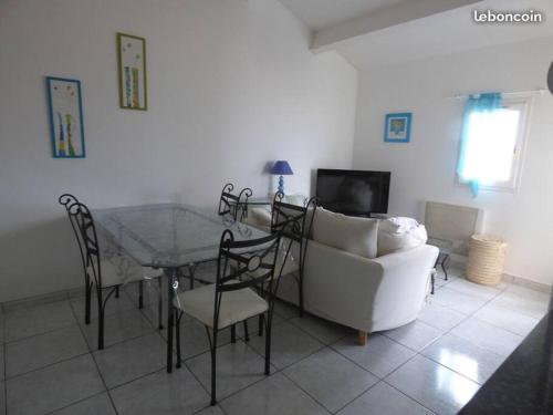 un soggiorno con tavolo e divano bianco di Appartement T3 climatisé avec vue sur mer a Fleury