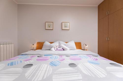 マリンスカにあるApartment Krebeljのベッドルーム1室(ピンクとブルーのベッドカバー付きの大型ベッド1台付)