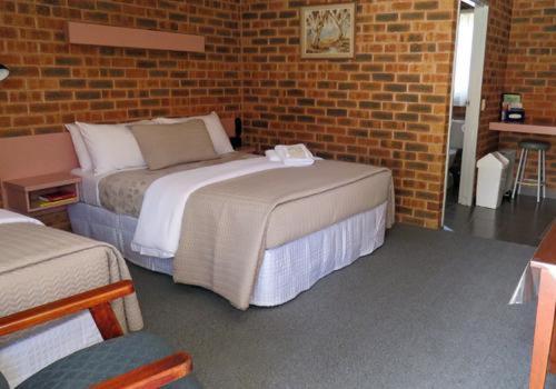a room with two beds and a brick wall at The Lydoun Motel in Chiltern