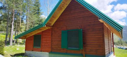 a small red building with green shutters at Apartman Djokovic in Žabljak