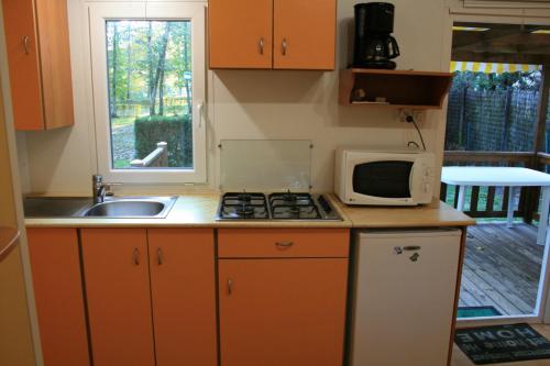 una pequeña cocina con microondas y fregadero en CAMPING ONLYCAMP LA VARENNE en Neung-sur-Beuvron