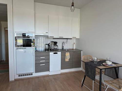 a kitchen with white appliances and a table with chairs at Near center w/ smart-TV, tram stop and gym visit in Tampere