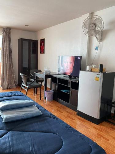 a room with a tv and a desk with a refrigerator at Zappa Guesthouse in Pattaya