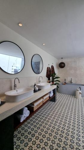 a bathroom with two sinks and two mirrors at VILLA CELAVI 15 in Kerobokan