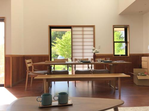 een kamer met tafels, stoelen en ramen bij LiveGRACE Villa Lake Kawaguchiko 富士河口湖 in Yamanashi