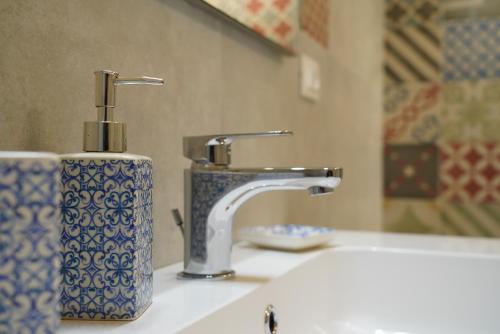 a bathroom sink with a faucet and a bottle of soap at Casetta Filippi - a POCHI PASSI dal CENTRO STORICO in Ceglie Messapica