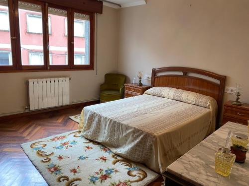 1 dormitorio con cama, mesa y alfombra en Apartamento de 4 habitaciones en Cabo de Cruz, en Boiro