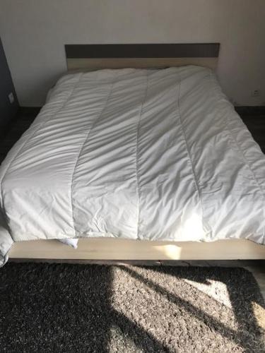 een ongeëvenaard bed met witte lakens op de vloer bij Location MAISON LE MANS in Rouillon
