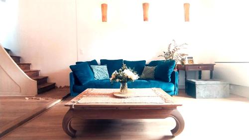 un salon avec un canapé bleu et une table basse dans l'établissement Les nids de la tour - Spa privé - wifi, à Saint-Émilion