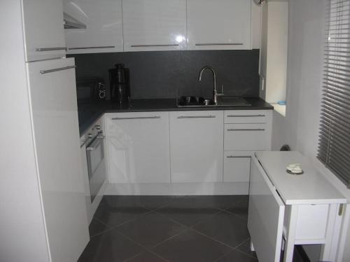une cuisine blanche avec des armoires blanches et un évier dans l'établissement BORD DE MER : CHARMANTE MAISON DE PECHEUR, à Yport