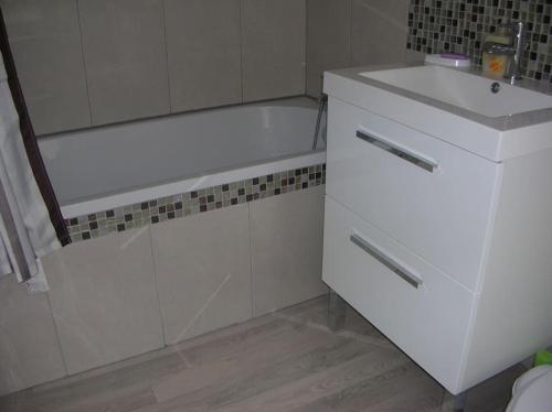 La salle de bains blanche est pourvue d'une baignoire et d'un lavabo. dans l'établissement BORD DE MER : CHARMANTE MAISON DE PECHEUR, à Yport