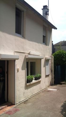 une maison avec deux plantes en pot dans une fenêtre dans l'établissement BORD DE MER : CHARMANTE MAISON DE PECHEUR, à Yport