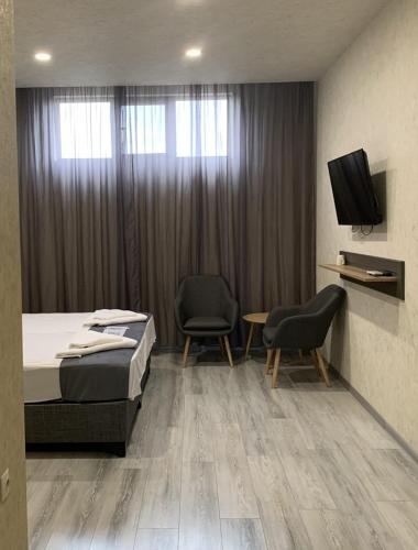 1 dormitorio con 1 cama, 2 sillas y TV en Стандартна стая Пламен, en Vratsa