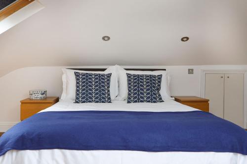 a bed with blue and white sheets and pillows at Bright and Modern 2 bed flat in London