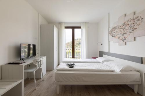 a white bedroom with a bed and a desk at Park Hotel Val Di Monte ***S in Malcesine