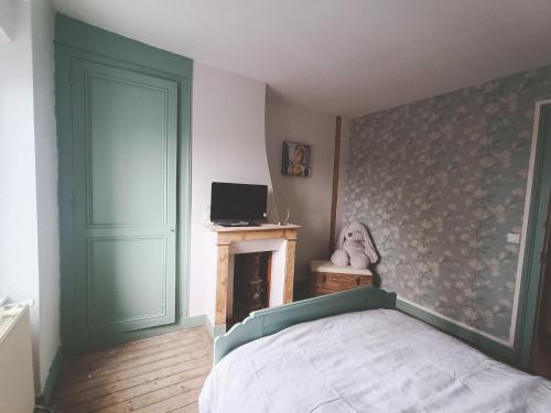 a bedroom with a bed and a tv and a fireplace at La Maison des Magnolias in Trouville-sur-Mer