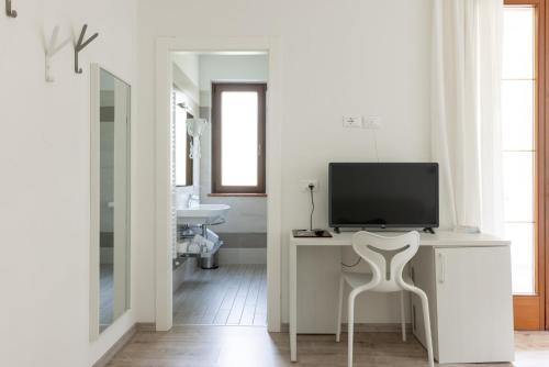a white bathroom with a tv on a desk with a chair at Park Hotel Val Di Monte ***S in Malcesine
