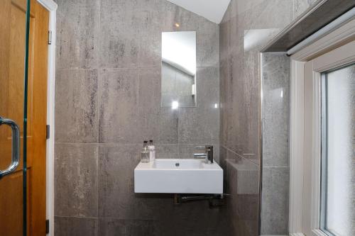 a bathroom with a white sink and a mirror at Bright and Modern 2 bed flat in London