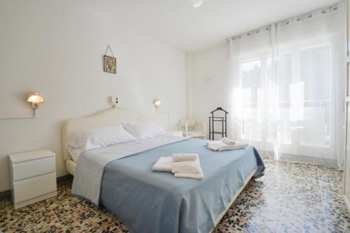 a white bedroom with a bed with towels on it at Hotel Maddalena in Marina di Ravenna