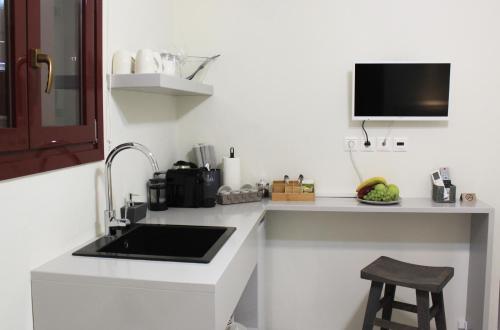 a kitchen with a sink and a counter with a stool at OUTOPOIA CAVE STUDIOS in Oia