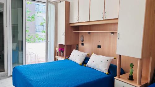 a bedroom with a blue bed with white pillows at Hotel Sorriso in Cattolica