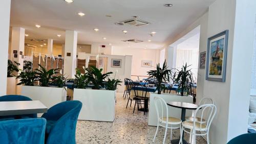 un restaurante con mesas, sillas y plantas en Hotel Sorriso, en Cattolica
