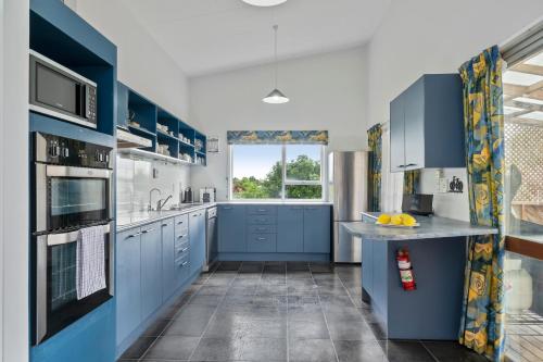 una cucina con armadi blu e piano di lavoro blu di The Family Hub a Taupo