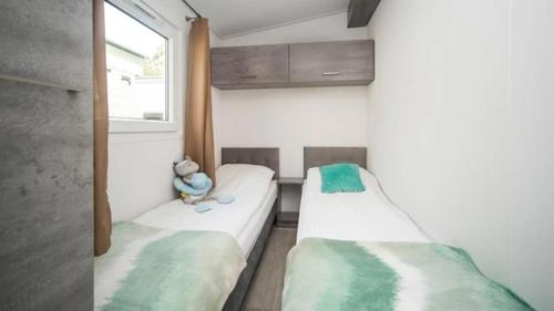 2 łóżka pojedyncze w pokoju z oknem w obiekcie domek kempingowy w Chałupach