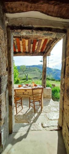 une table et un banc dans un bâtiment en pierre avec vue dans l'établissement Abbaye de Bodon - Provence, à Saint-May