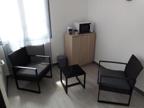 Habitación con 2 sillas y TV en un armario. en Les chambres du Montagut, en Saint-Sauveur-de-Montagut
