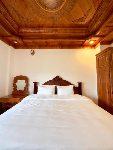 a bedroom with a large white bed with a wooden ceiling at Hotel Hoàng My in Pleiku
