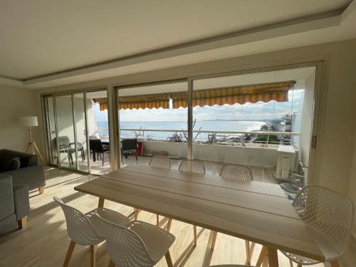 - une table et des chaises dans le salon doté d'une grande fenêtre dans l'établissement 06AO - Superbe appartement avec vue mer exceptionnelle, à Villeneuve-Loubet