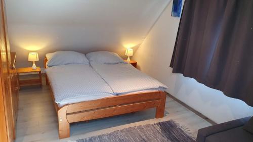 a bed in a room with two lamps on two tables at Aszófői Panoráma Apartmanház in Aszófő