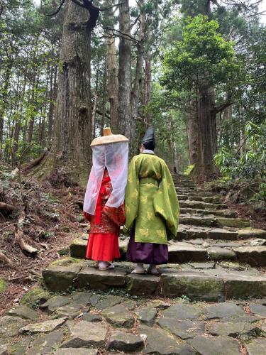 two people walking down a stone path in a forest at ゲストハウス れんげ苑 in Shimosato